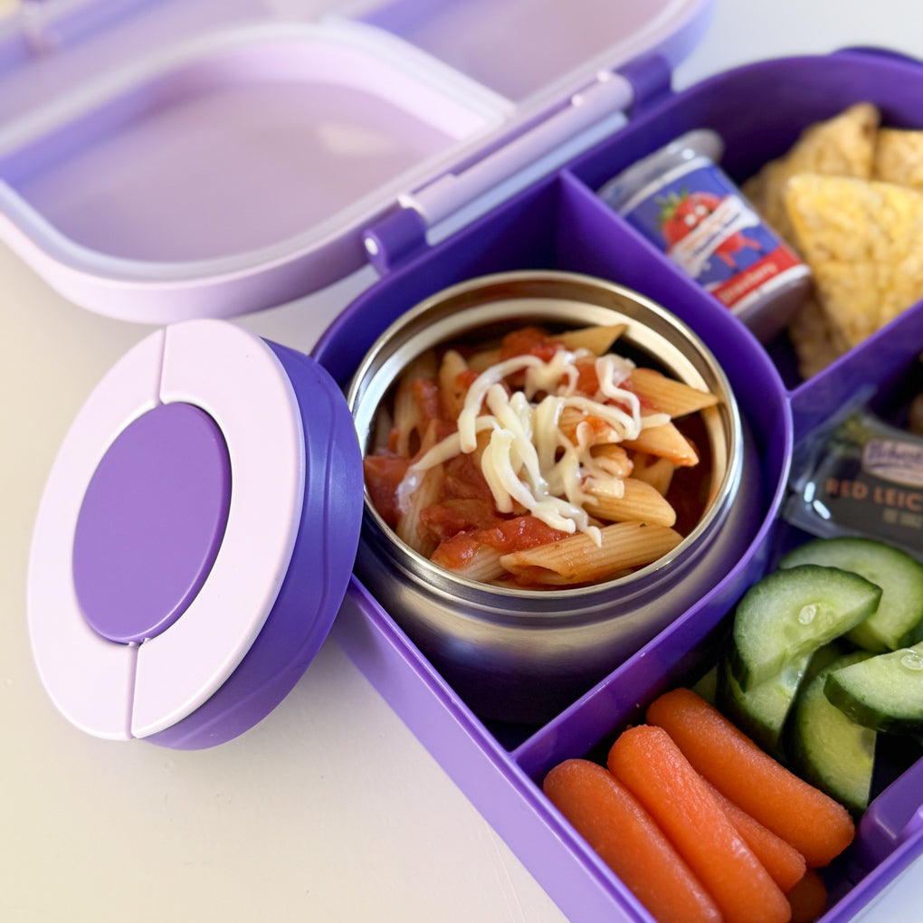 A purple compartment lunchbox for kids containing a small stainless steel food thermos filled with cooked pasta and grated cheese.