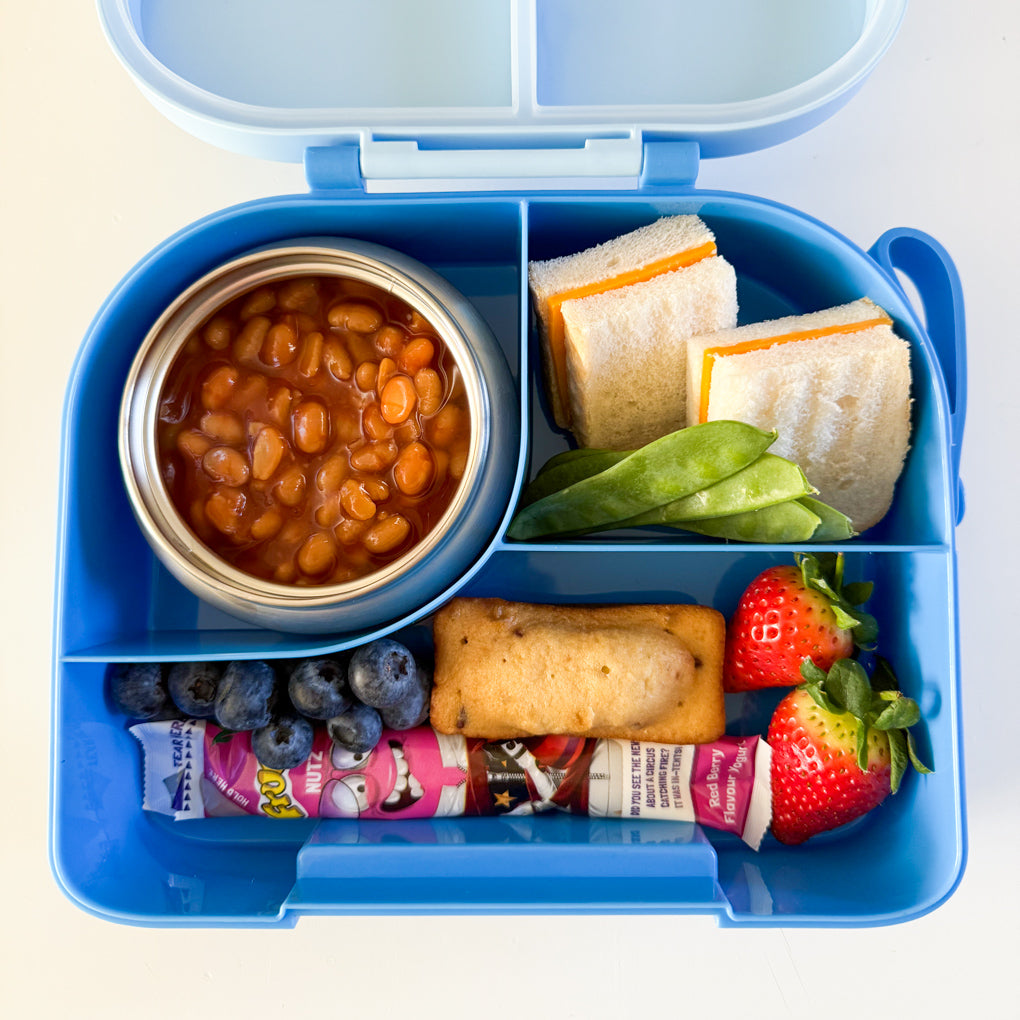 A blue compartment lunchbox with a small stainless steel food thermos inside. Packed with baked beans, half a cheese sandwich, sugar snap peas, cake bar, blueberries and strawberries.