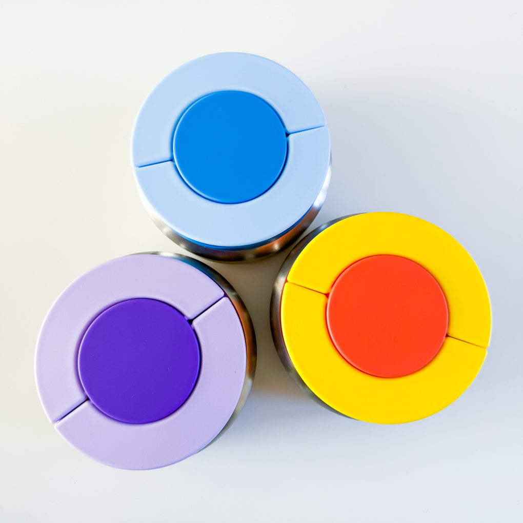 Three small stainless steel food thermoses with brightly coloured lids in blue, purple and yellow / orange colourways.