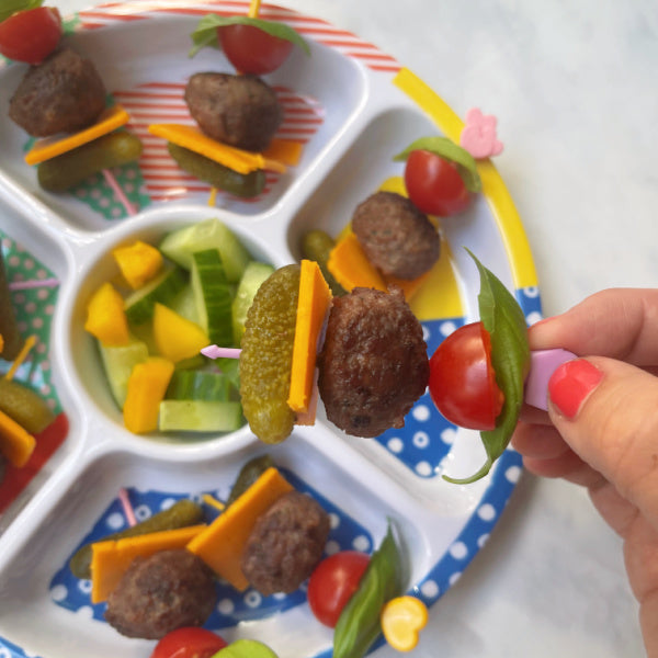 Meatballs, mini gherkins, burger cheese, cherry tomato and basil on Pick Sticks in a fun brightly coloured kids plate.