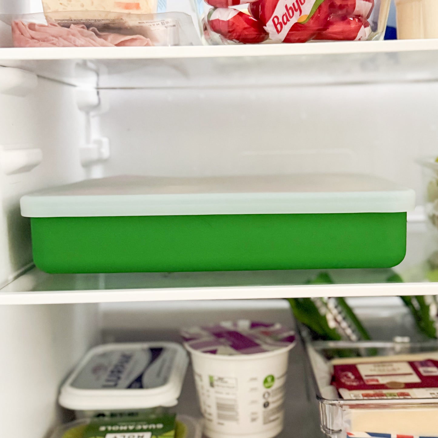 Green compartment snack box with lid in a refrigerator.