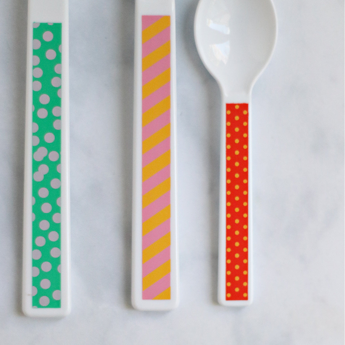 a close up of the cutlery handles detailing the colourful patterns on each utensil.