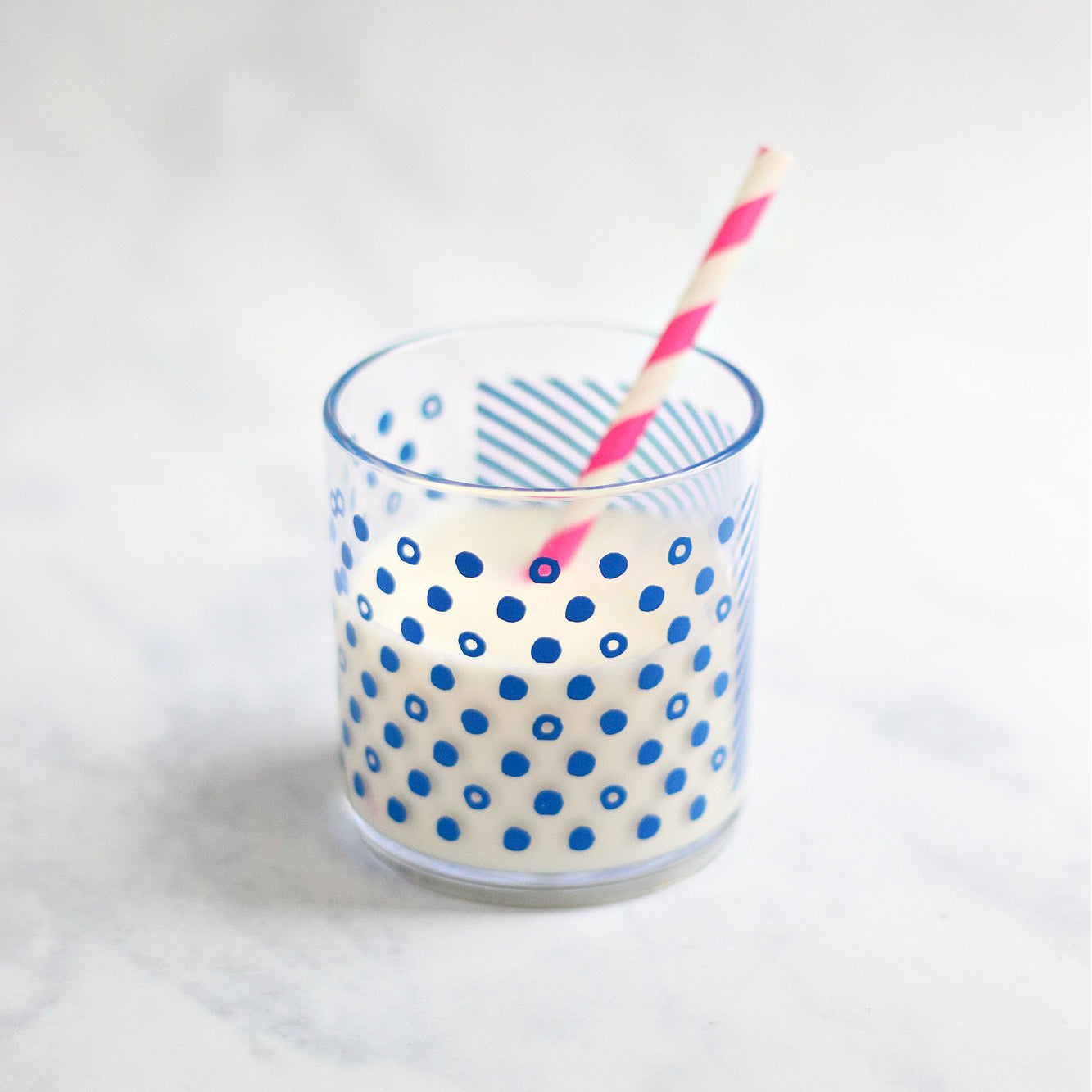 The classic tumber filled with milk and a pink and white striped straw.